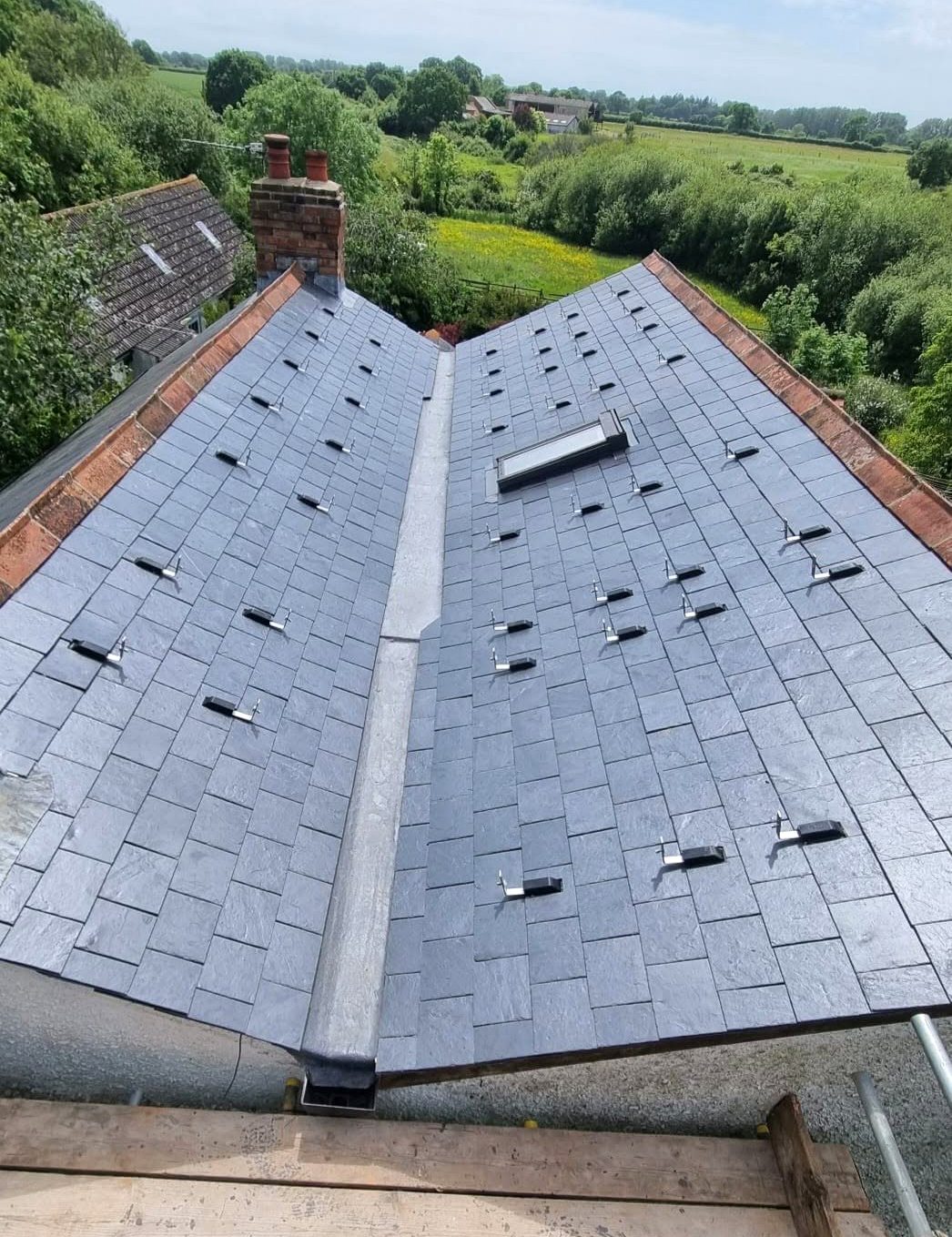 A freshly completed slate roof by Shoreside Roofing against a blue sky